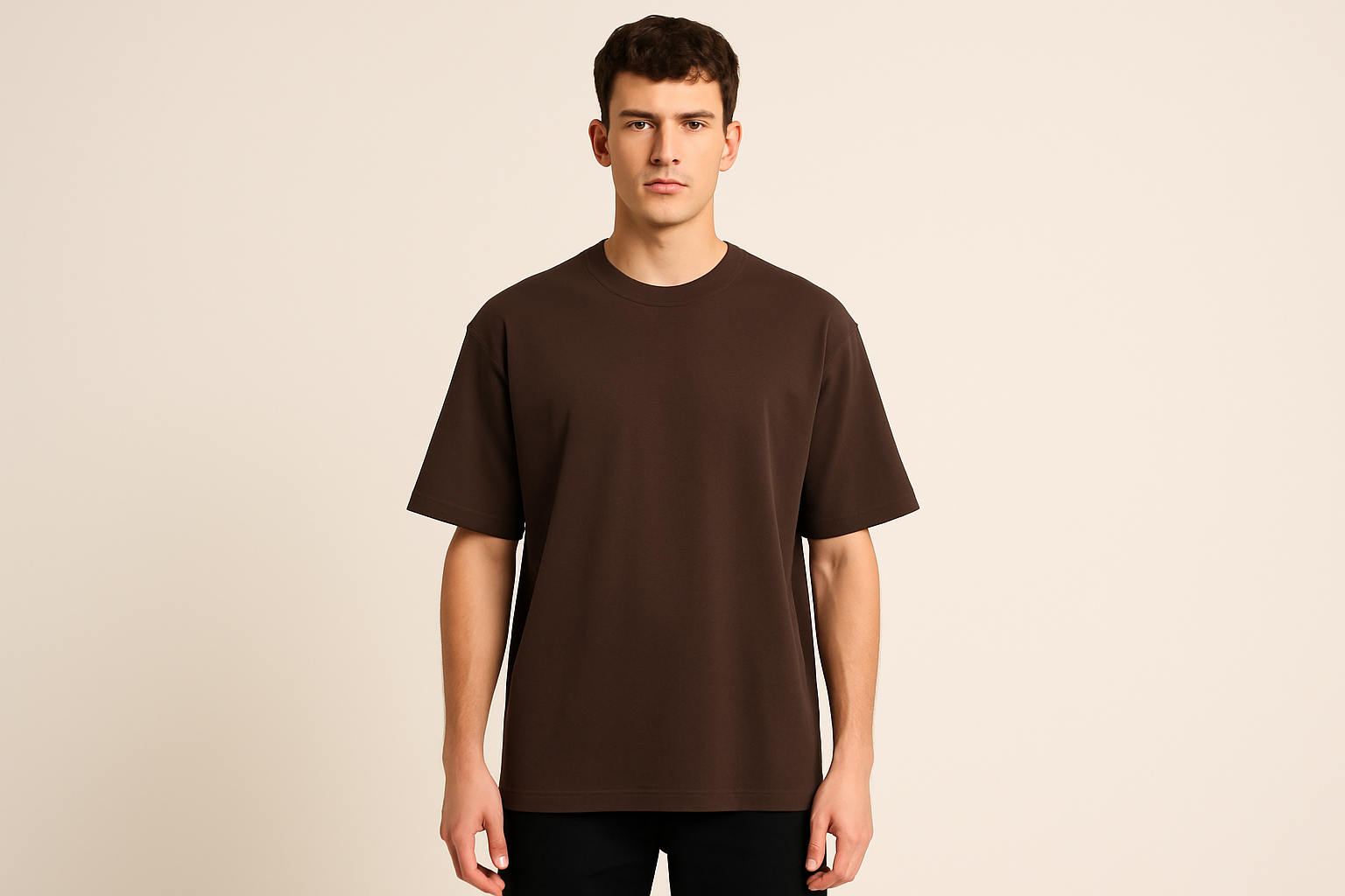 Professional e-commerce product photography of a male model wearing an oversized dark brown crew neck t-shirt, standing straight facing camera with hands relaxed at sides, wearing dark pants against a neutral beige background with studio lighting