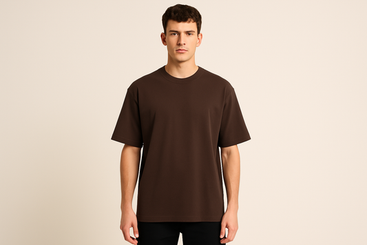 Professional e-commerce product photography of a male model wearing an oversized dark brown crew neck t-shirt, standing straight facing camera with hands relaxed at sides, wearing dark pants against a neutral beige background with studio lighting